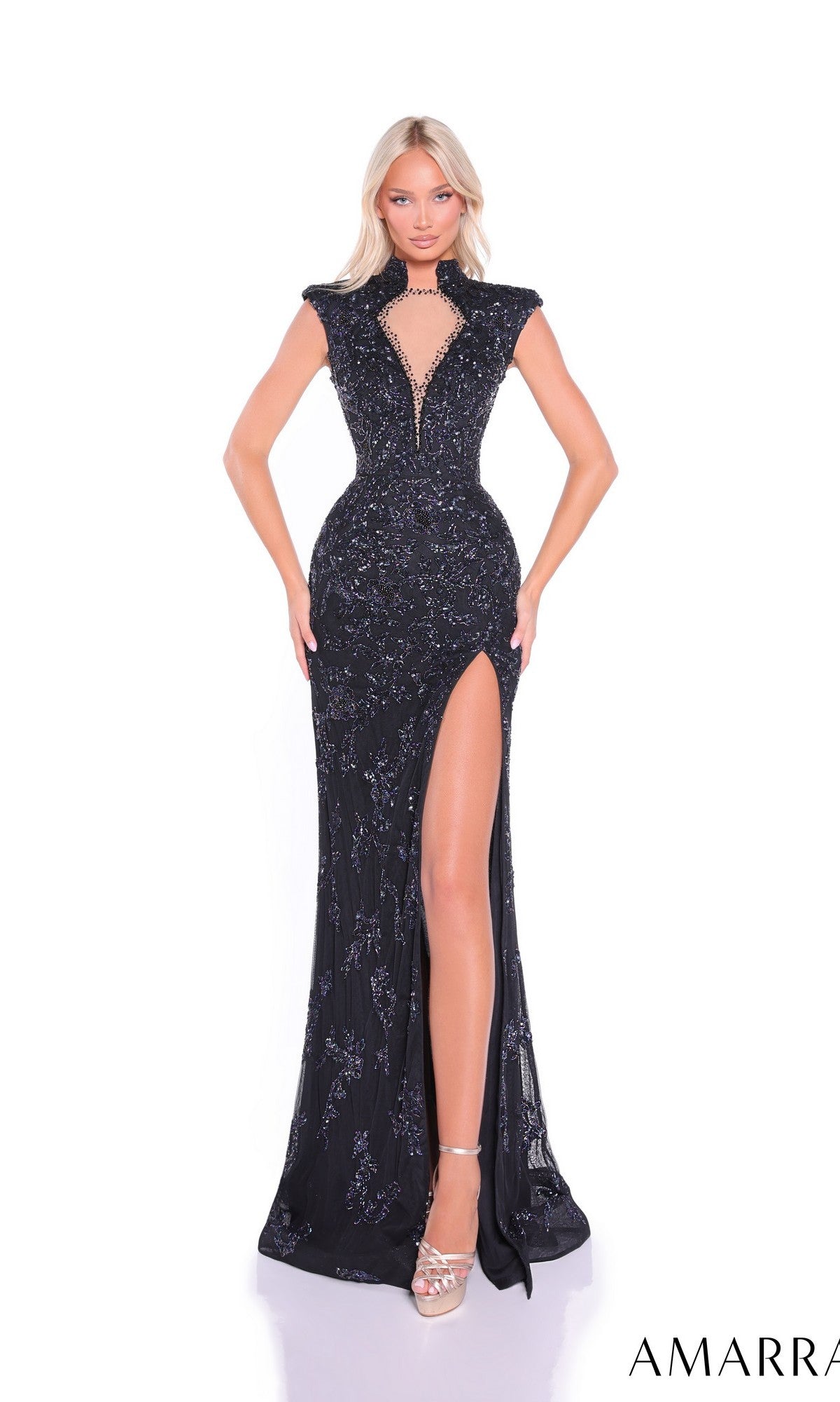 A woman stands against a white background wearing the Amarra 89191, a long, form-fitting black prom dress with embellishments, a high slit, and a deep V neckline.